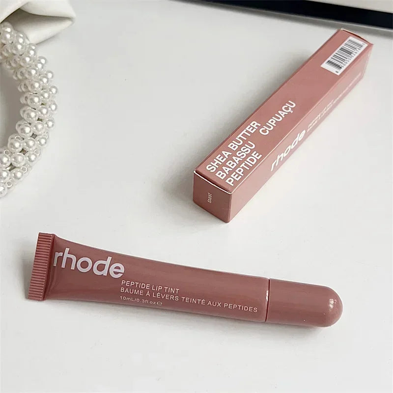 Rhode peptide lip tint tube and matching box on white surface Flavored moisturizing lip balm for dry lips in rosy nude shade