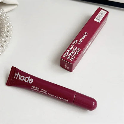 Rhode peptide lip tint tube and box in deep berry shade on white surface Flavored moisturizing lip balm for dry lips.