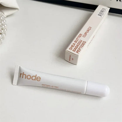 EtherealBe white Rhode lip tube and box on white surface showcasing Flavored moisturizing lip balm for dry lips simple packaging