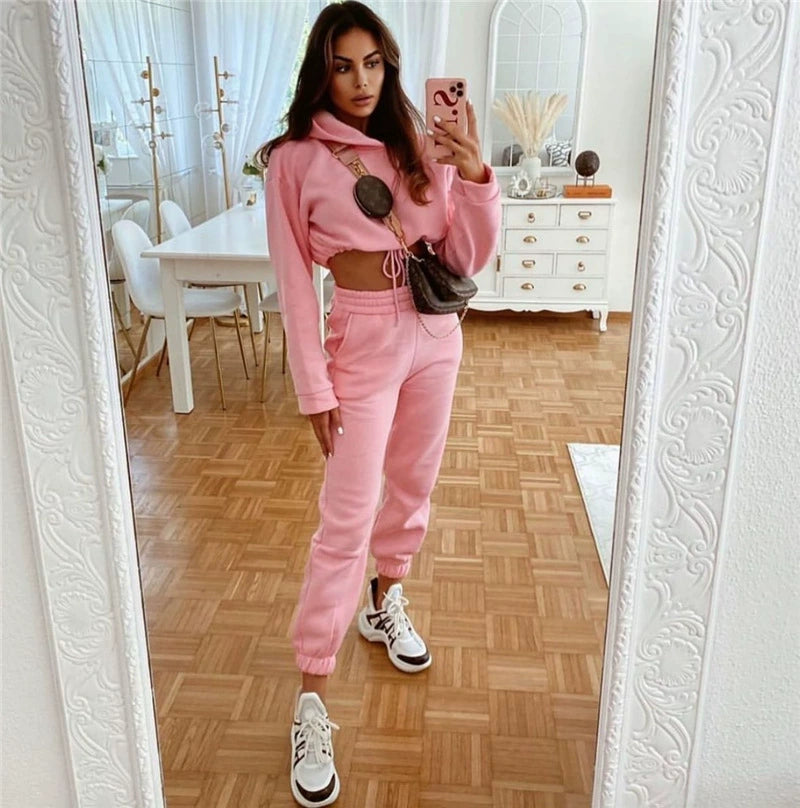 Stylish model showcasing a trendy women's hoodie and joggers set in pink with stylish sneakers
