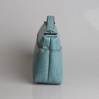 Side view of a luxurious faux crocodile makeup bag in blue with a sleek design and stylish finish