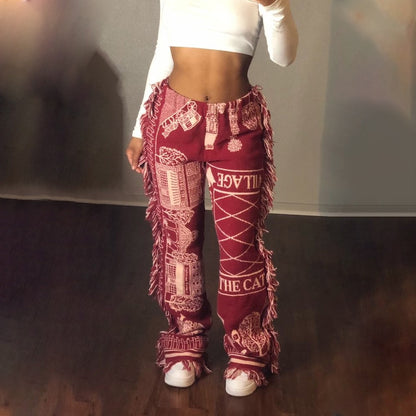 Model wearing maroon tassel patchwork striped pants with fringe details and white crop top and sneakers