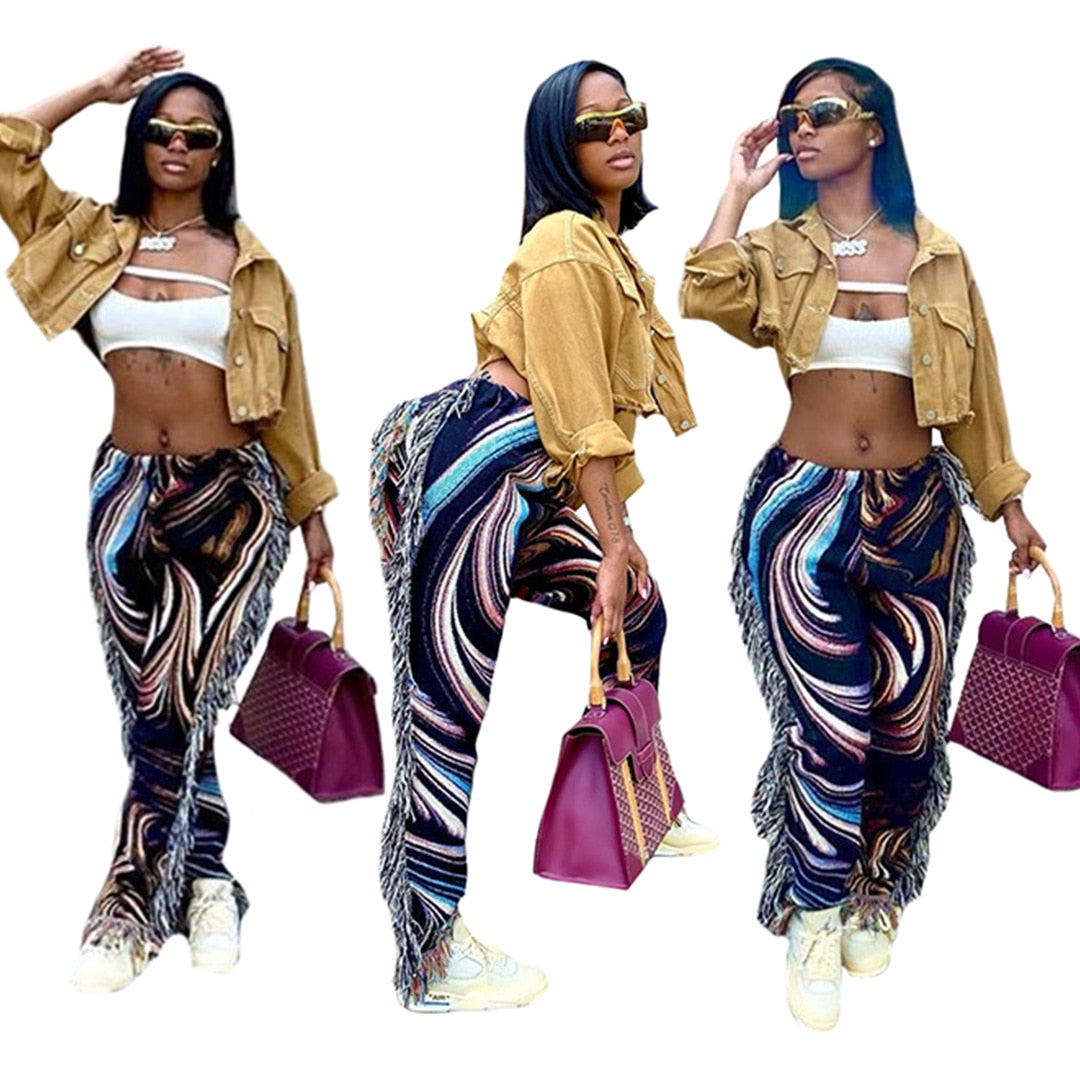 Model wearing tassel patchwork striped pants with tan cropped jacket white crop top and purple bag
