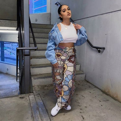 Woman wearing tassel patchwork striped pants with floral panels white crop top denim jacket and sneakers