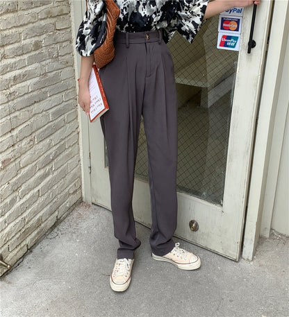 Model wearing Formal straight leg suit office trousers for women. Gray high waist pleated pants with sneakers and patterned blouse