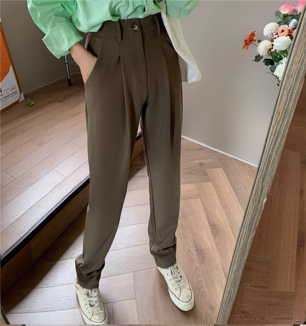 Woman in brown Formal straight leg suit office trousers for women. with green top and sneakers on wood floor