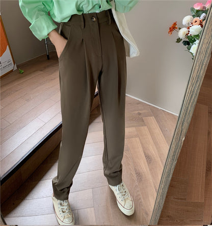 Woman in brown Formal straight leg suit office trousers for women. with green top and sneakers on wood floor