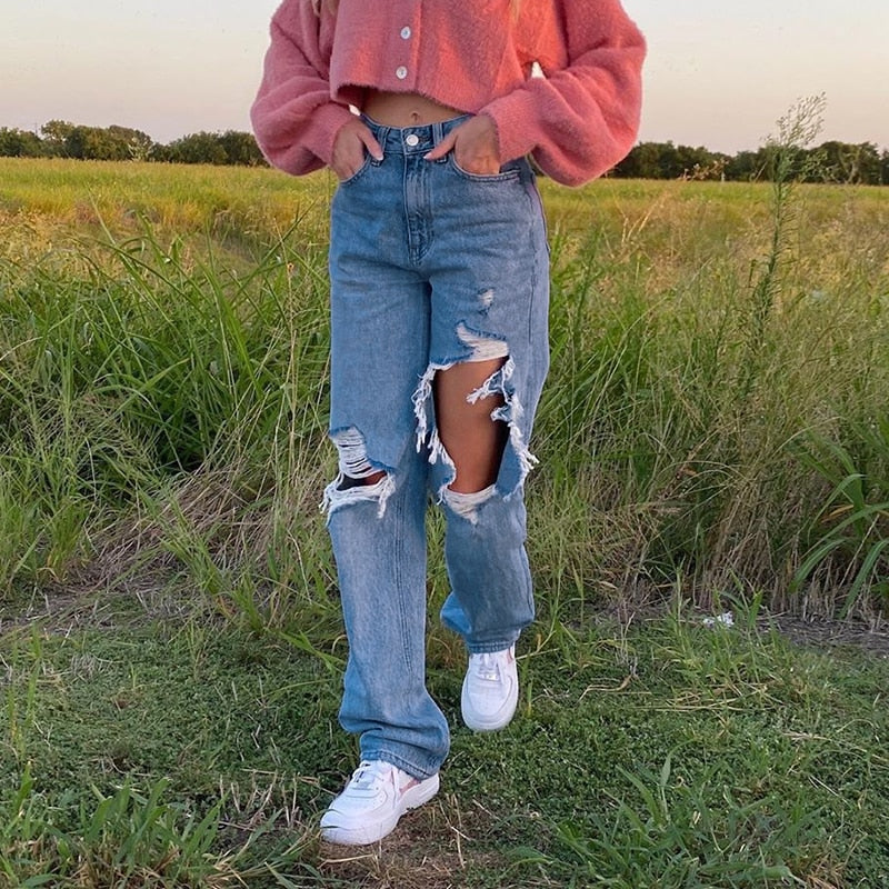 Model wearing hollow out ripped denim pants with large thigh holes high waist casual look pink cropped sweater