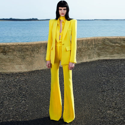 Model wearing bright yellow tailored flare pants blazer set for women with high waisted flares and structured blazer by the sea