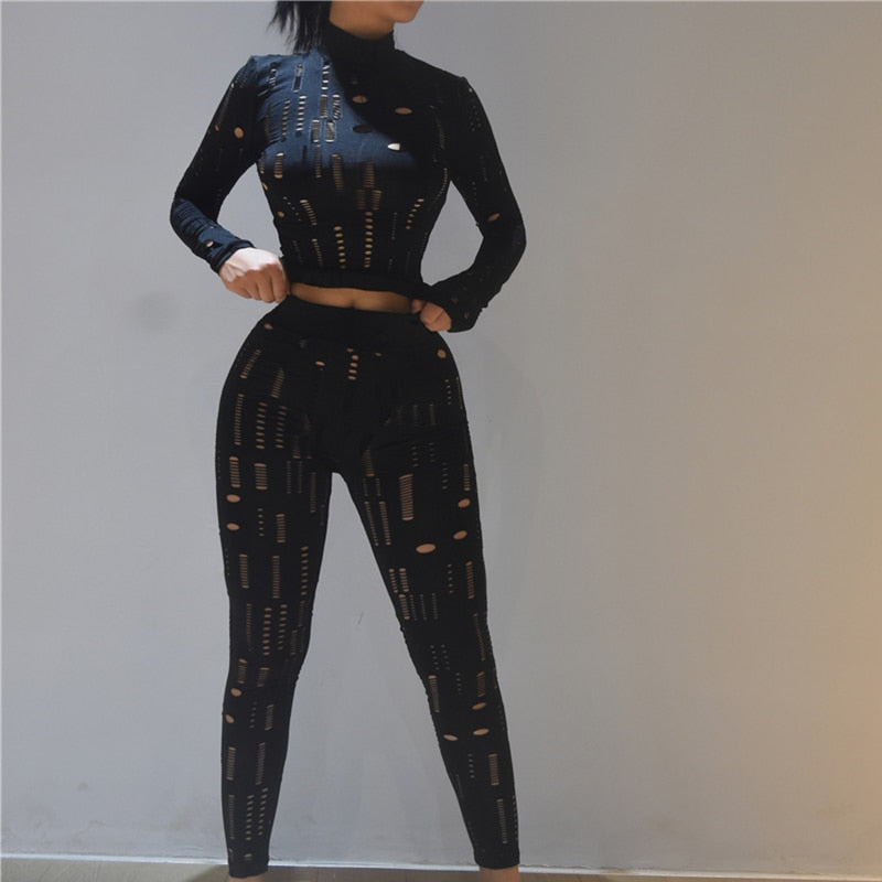 Model wearing black cutout women's biker style two piece set with long sleeve crop top and high waist leggings