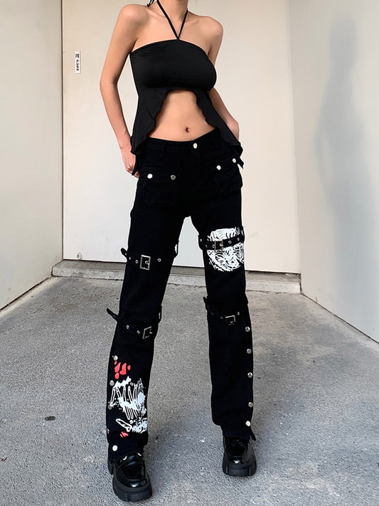 Model wearing black mall goth cargo pants women with buckle straps white skull graphics button studs and platform shoes
