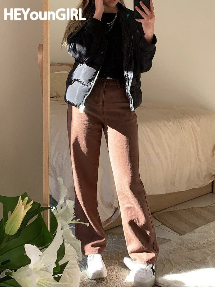 Woman mirror selfie wearing vintage high waist wide leg pants in brown with black puffer jacket and white sneakers