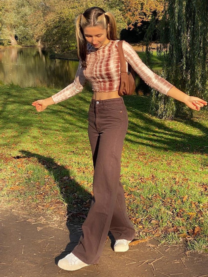 Woman wearing brown vintage high waist wide leg pants with white sneakers and tie dye crop top in park