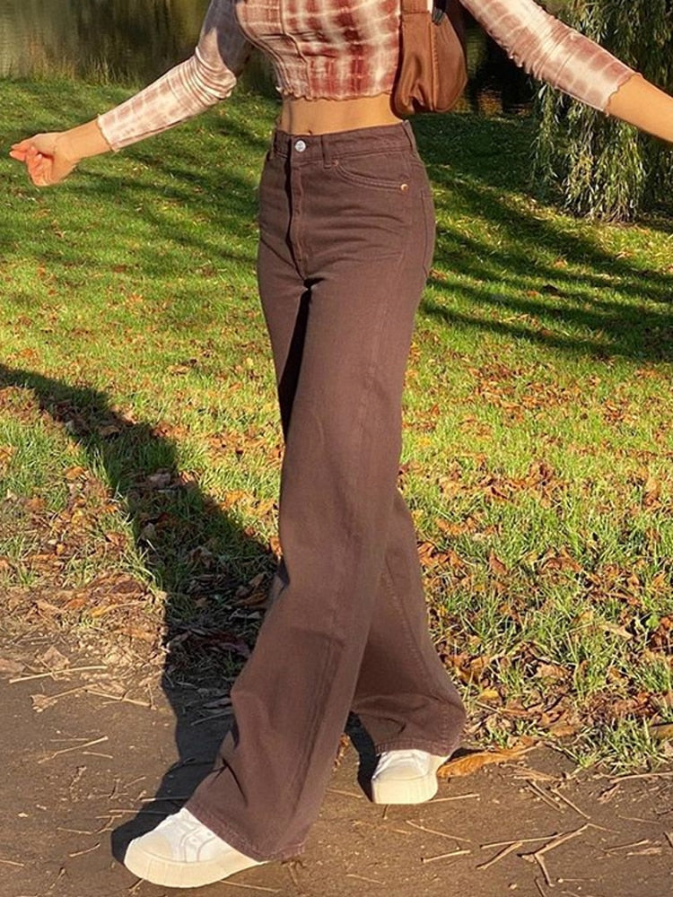 Model wearing vintage high waist wide leg pants in chocolate brown with cropped long sleeve top and white sneakers in park