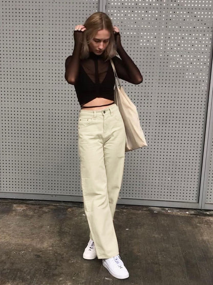 Model wearing vintage high waist wide leg pants in cream with black sheer crop top white sneakers tote