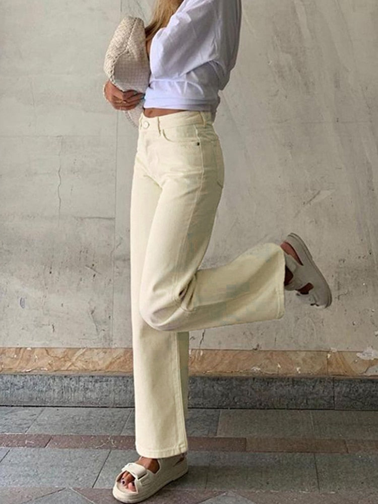 Model wearing cream vintage high waist wide leg pants styled with cropped white top and woven clutch
