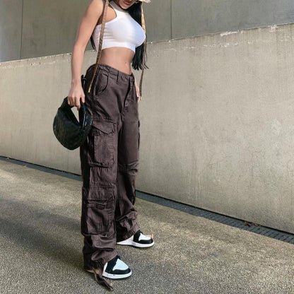 Model wearing women's low waist cargo jeans in dark brown with multiple pockets paired with white crop top and sneakers