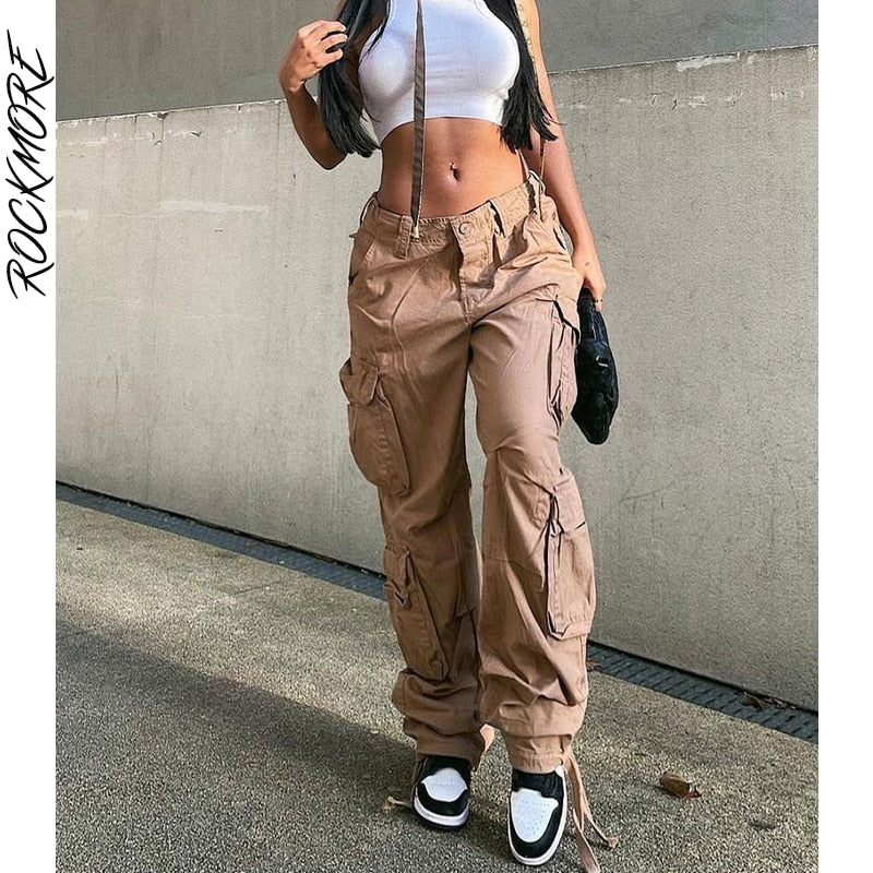 Model wearing women's low waist cargo jeans in tan with multiple pockets tied ankles and white crop top