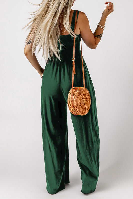 Back view of a green smocked wide leg jumpsuit paired with a stylish round handbag