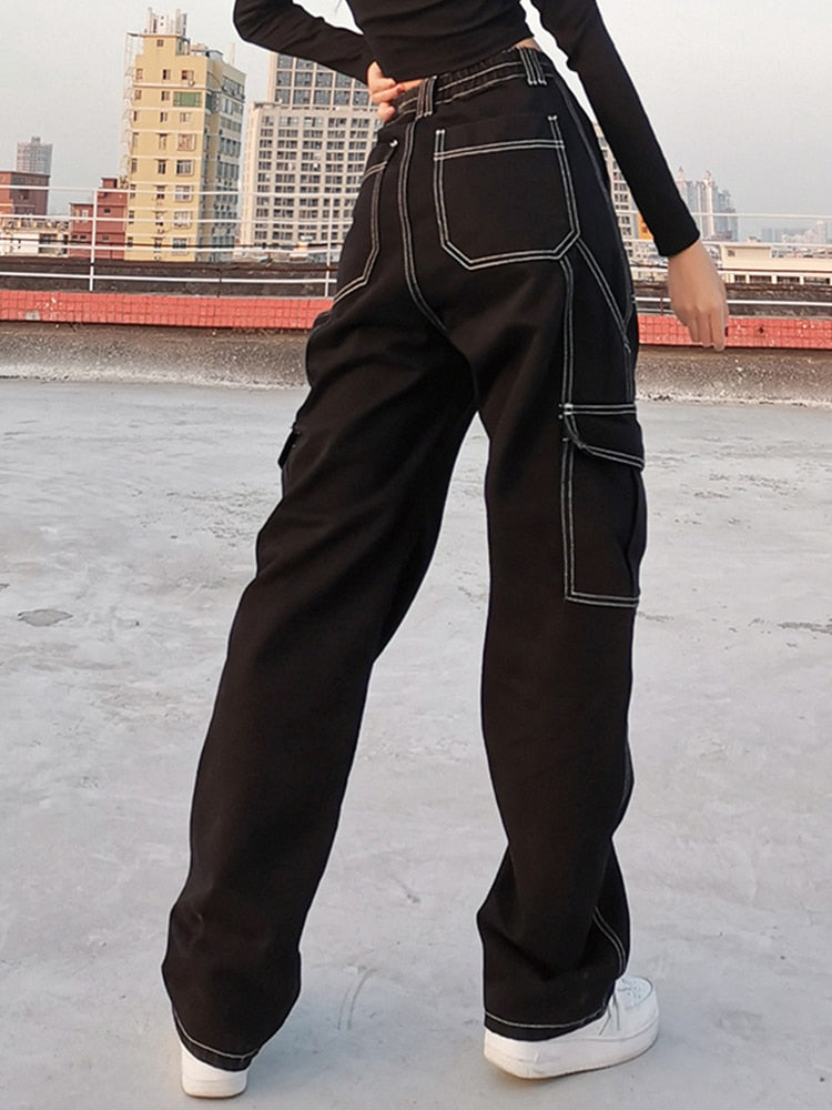 Back view of model wearing EtherealBe black baggy cargo jeans for women with white contrast stitching and cargo pockets