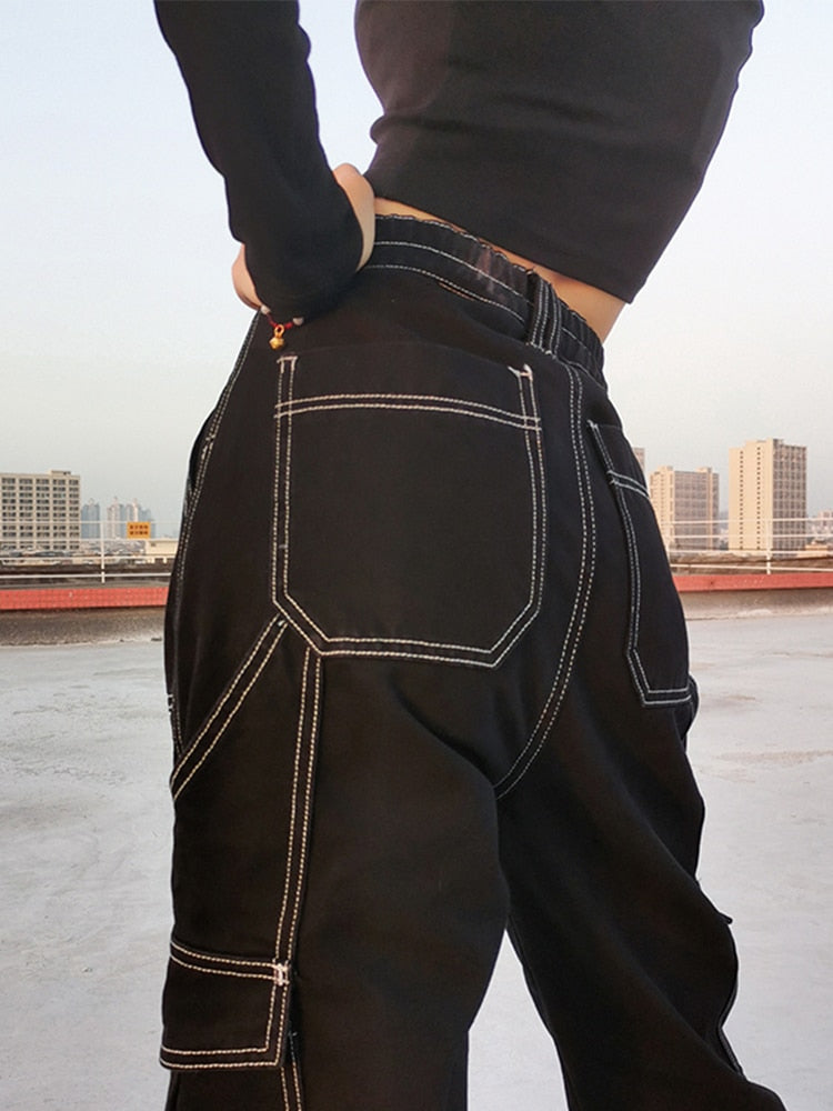 Black baggy cargo jeans for women with white contrast stitching and cargo pockets styled with black cropped top