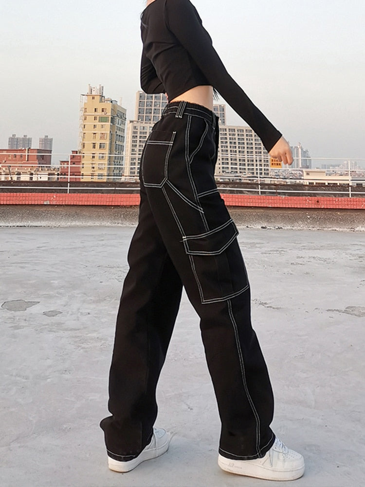 Side profile of black baggy cargo jeans for women with white contrast stitching and large side pockets