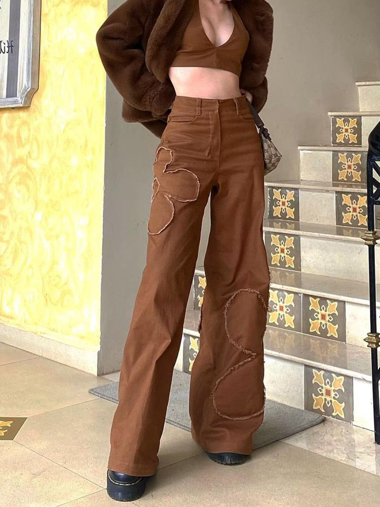 Model wearing brown baggy cargo jeans for women with circular patchwork and high waist paired with crop top