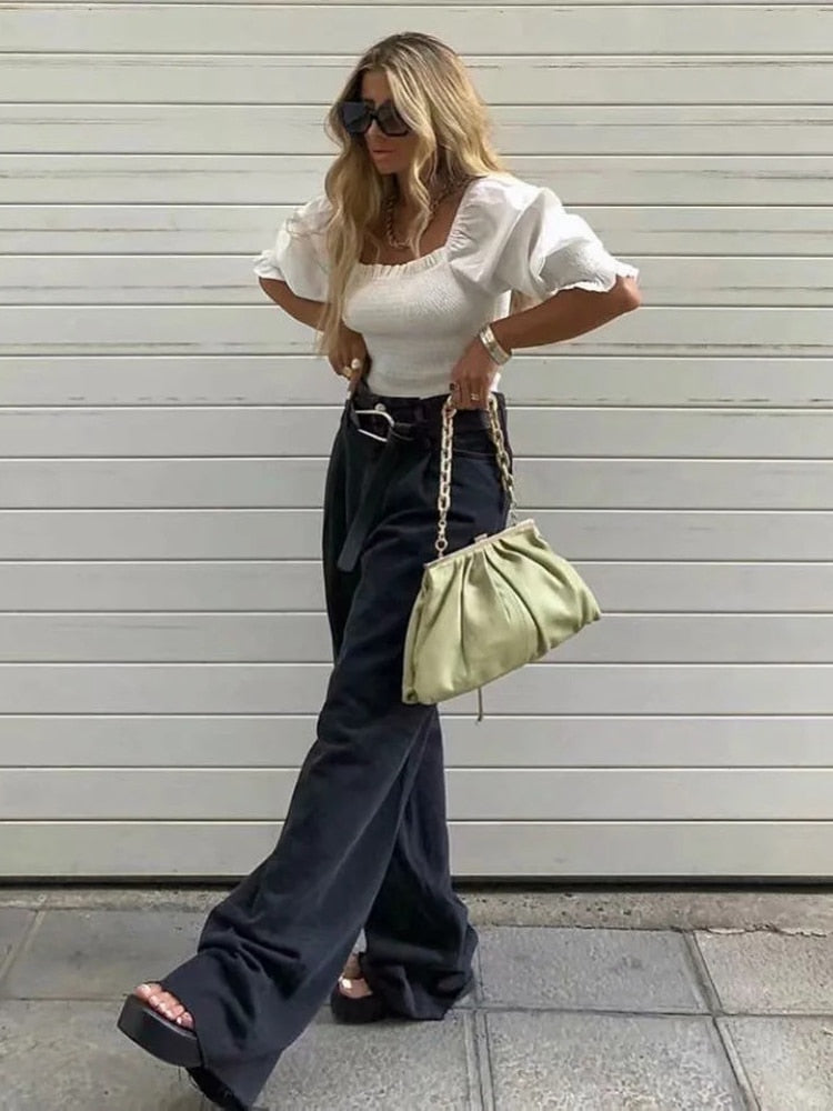 Stylish model wearing womens straight leg high waist jeans paired with a white top and green bag