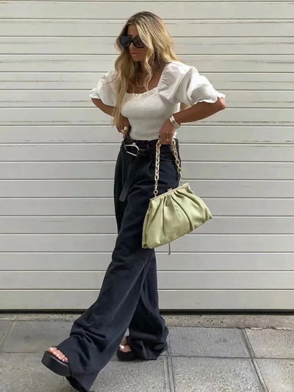 Stylish model wearing womens straight leg high waist jeans paired with a white top and green bag