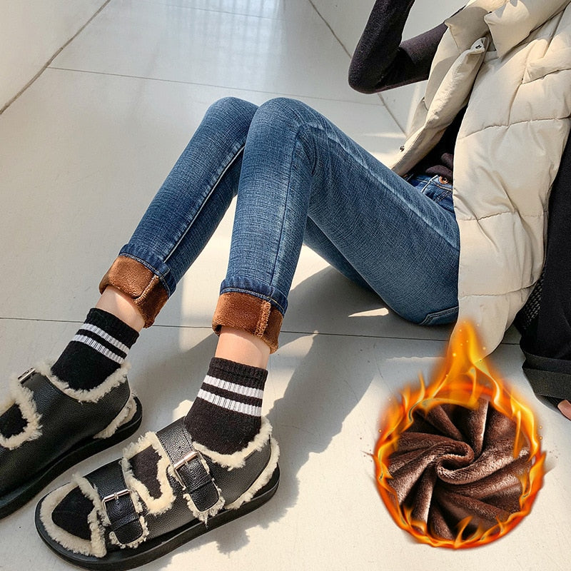 Woman sitting wearing blue fleece lined skinny jeans for women rolled cuff showing brown fleece lining